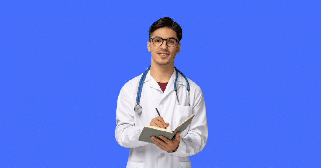 Médico jovem de jaleco branco com estetoscópio azul no pescoço, segurando um caderno e sorrindo, sobre fundo azul.