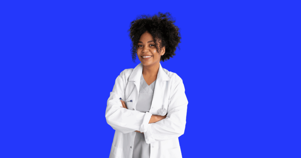 Médica sorridente de braços cruzados, usando jaleco branco e estetoscópio no pescoço, com roupa cinza por baixo e fundo azul vibrante.