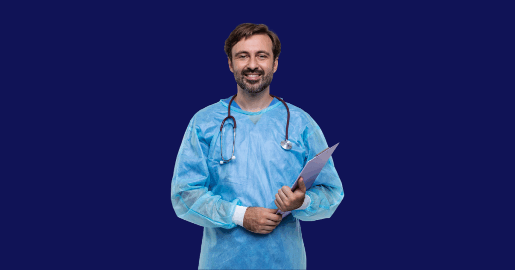Médico vestindo um avental cirúrgico azul e um estetoscópio em volta do pescoço, sorri para a frente enquanto segura uma prancheta rosa na mão esquerda. O fundo da imagem é azul escuro.