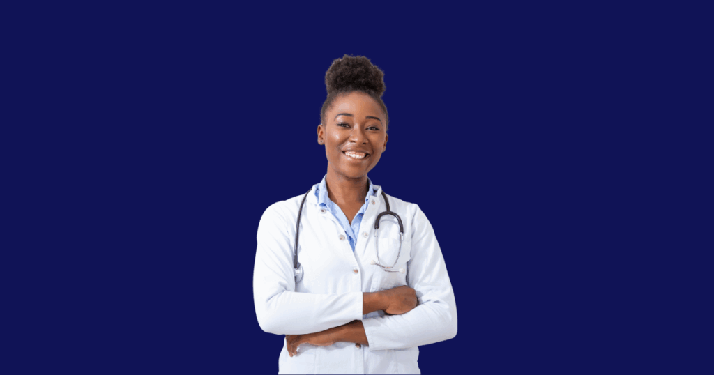 Uma médica negra jovem, com um coque alto e sorriso, está com os braços cruzados, usando um jaleco branco e estetoscópio.