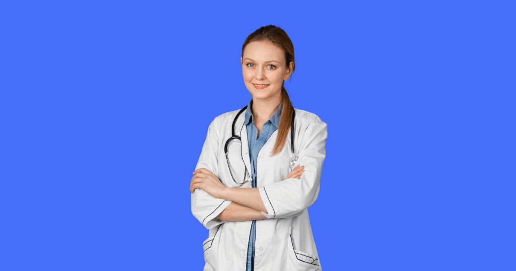 Uma jovem médica de jaleco branco, camisa jeans e estetoscópio no pescoço está com os braços cruzados e sorri para frente. O fundo da imagem é azul sólido.