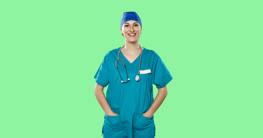 Uma médica de uniforme cirúrgico verde-água, gorro azul e estetoscópio, sorri para a câmera com as mãos nos bolsos.