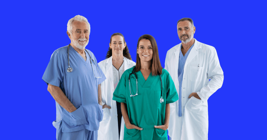 Grupo de quatro profissionais da saúde, incluindo médicos e médicas, usando jalecos e estetoscópios, posando com expressão amigável sobre fundo azul.