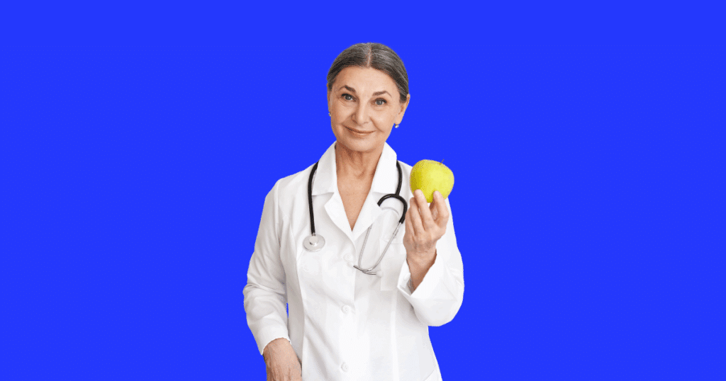 Nutricionista sorridente de jaleco branco e estetoscópio segurando uma maçã verde, representando saúde e cuidados profissionais.