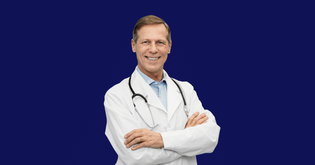 Médico sorridente vestindo jaleco branco e estetoscópio cruza os braços enquanto olha para a câmera. Fundo azul escuro sólido. Imagem ilustrativa para conteúdo sobre DMED e obrigações médicas.
