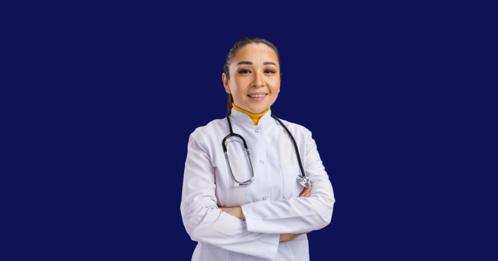 Médica sorridente vestindo jaleco branco e estetoscópio cruza os braços enquanto olha para a câmera. Fundo azul escuro sólido. Imagem ilustrativa para conteúdo sobre Recibo de Pagamento Autônomo (RPA).