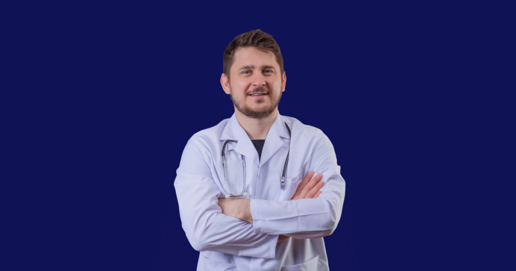 Médico vestindo jaleco branco e estetoscópio cruza os braços enquanto olha para a câmera. Fundo azul escuro sólido. Imagem ilustrativa para conteúdo sobre como escolher um escritório de contabilidade.